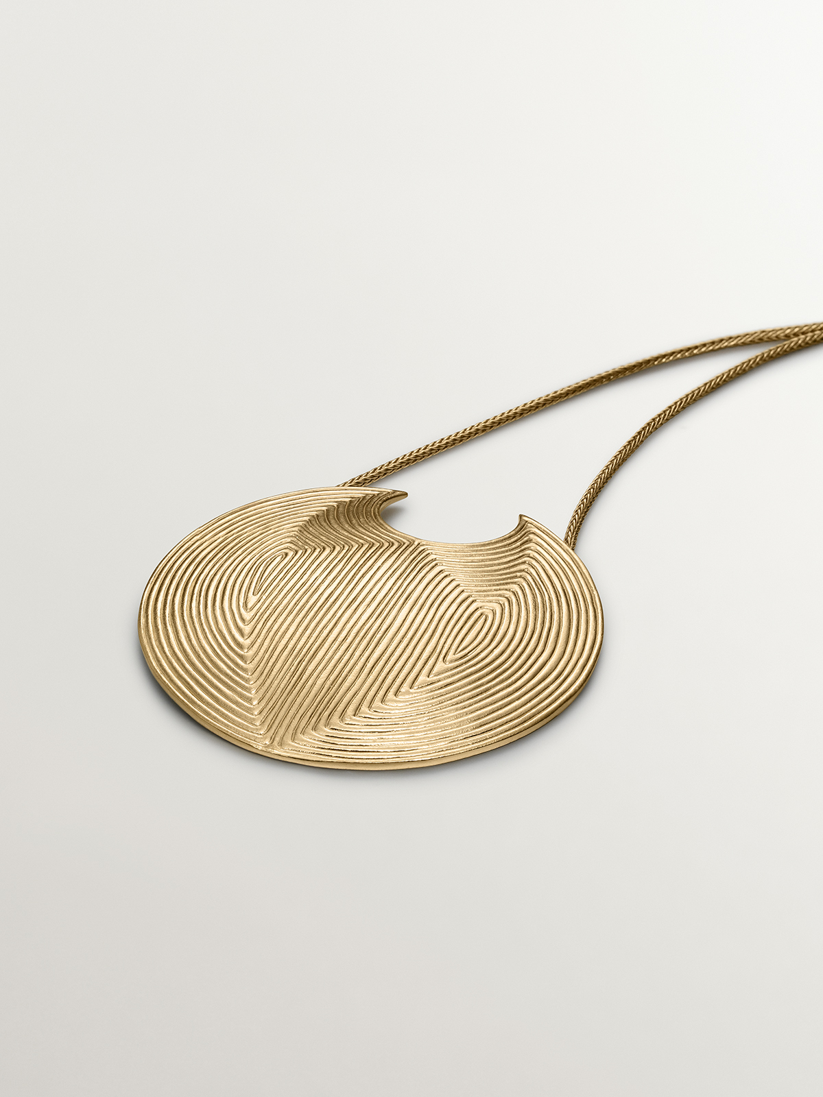 Large circular pendant made of 925 silver, bathed in 18K yellow gold with relief.