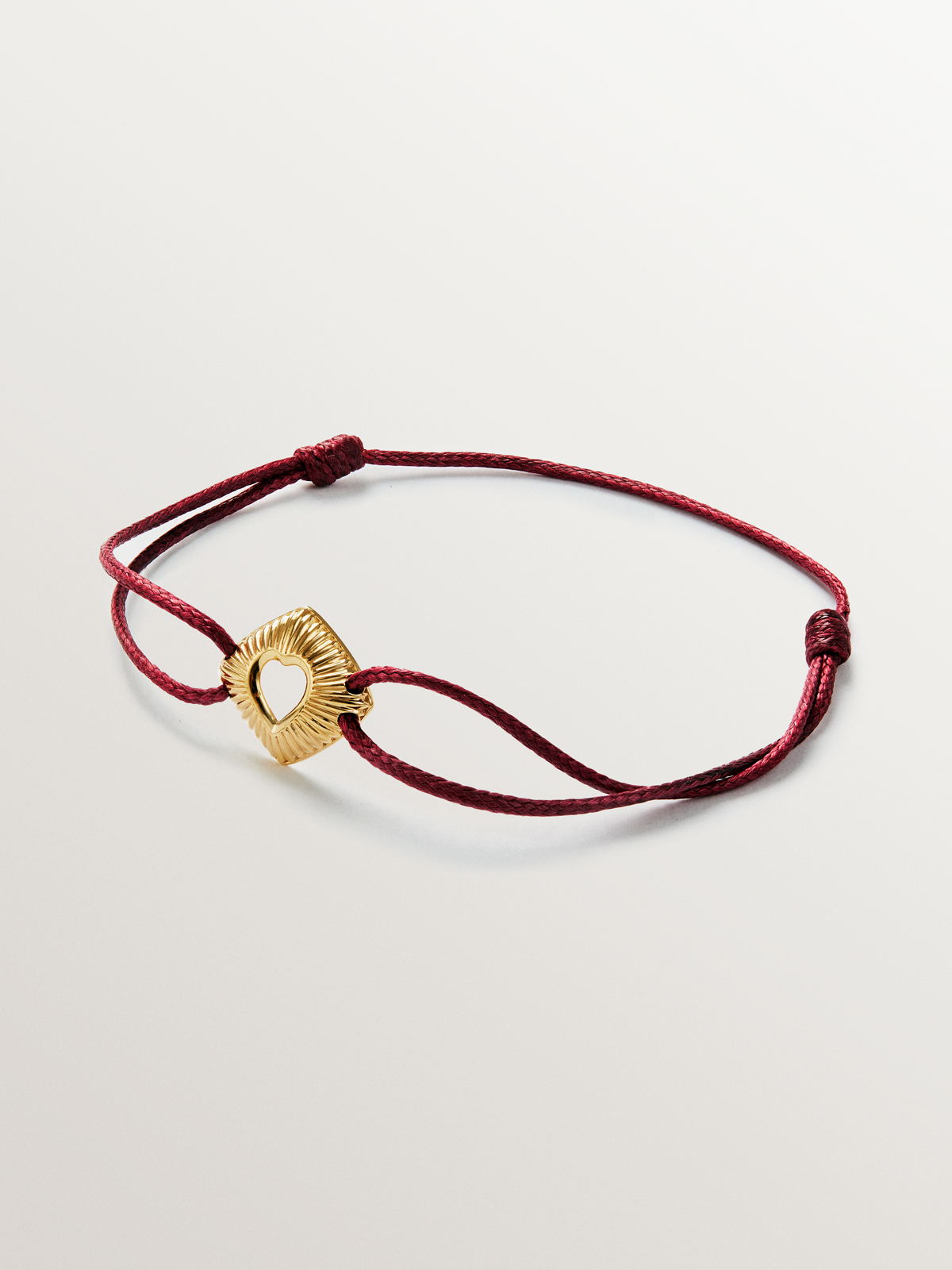 Pulsera de plata 925 bañada en oro amarillo de 18K con forma de corazón en textura de guilloché y con cuerda roja