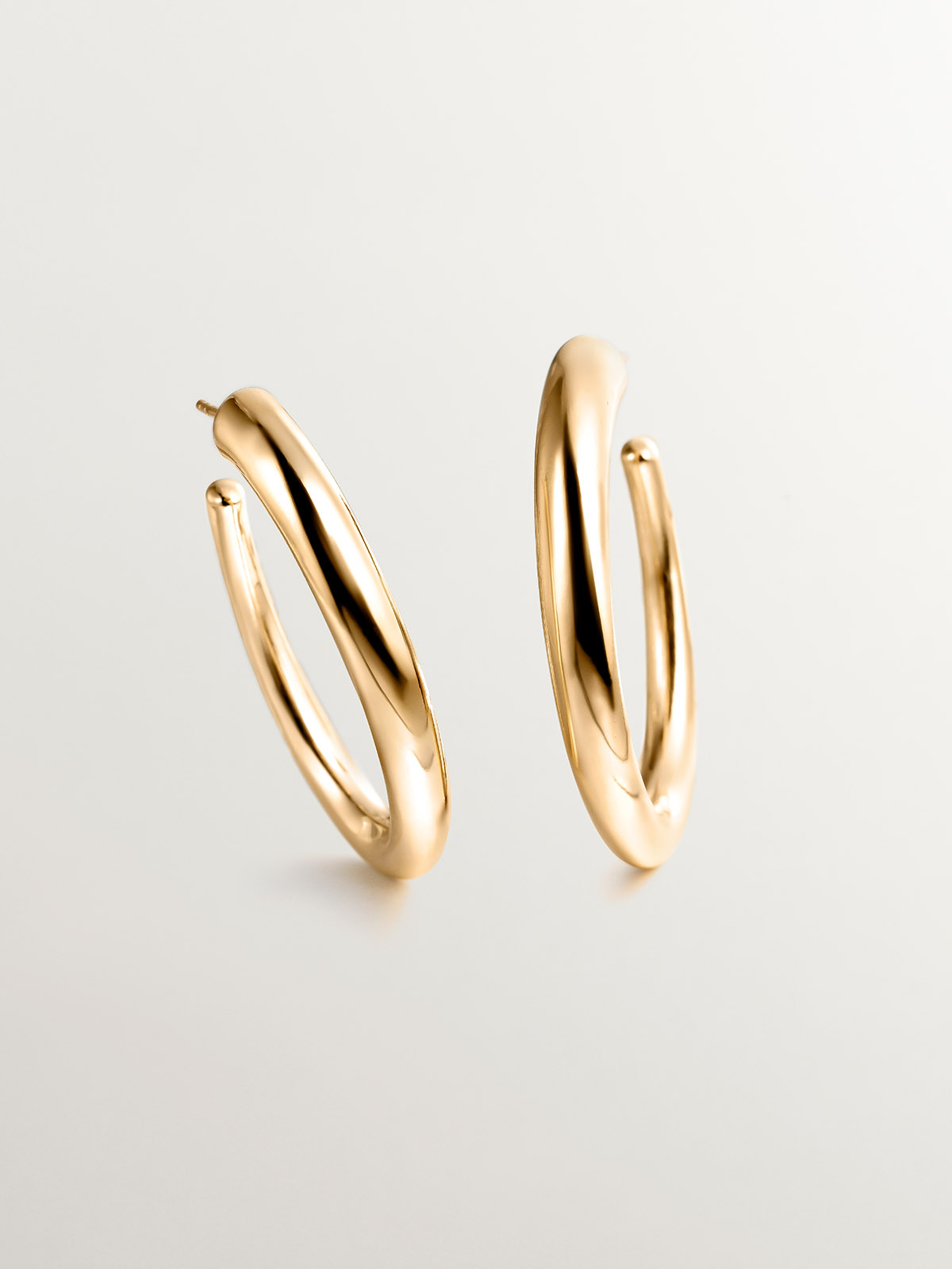 Large hoop earrings made of 925 silver, coated in 18K yellow gold, with an oval shape.