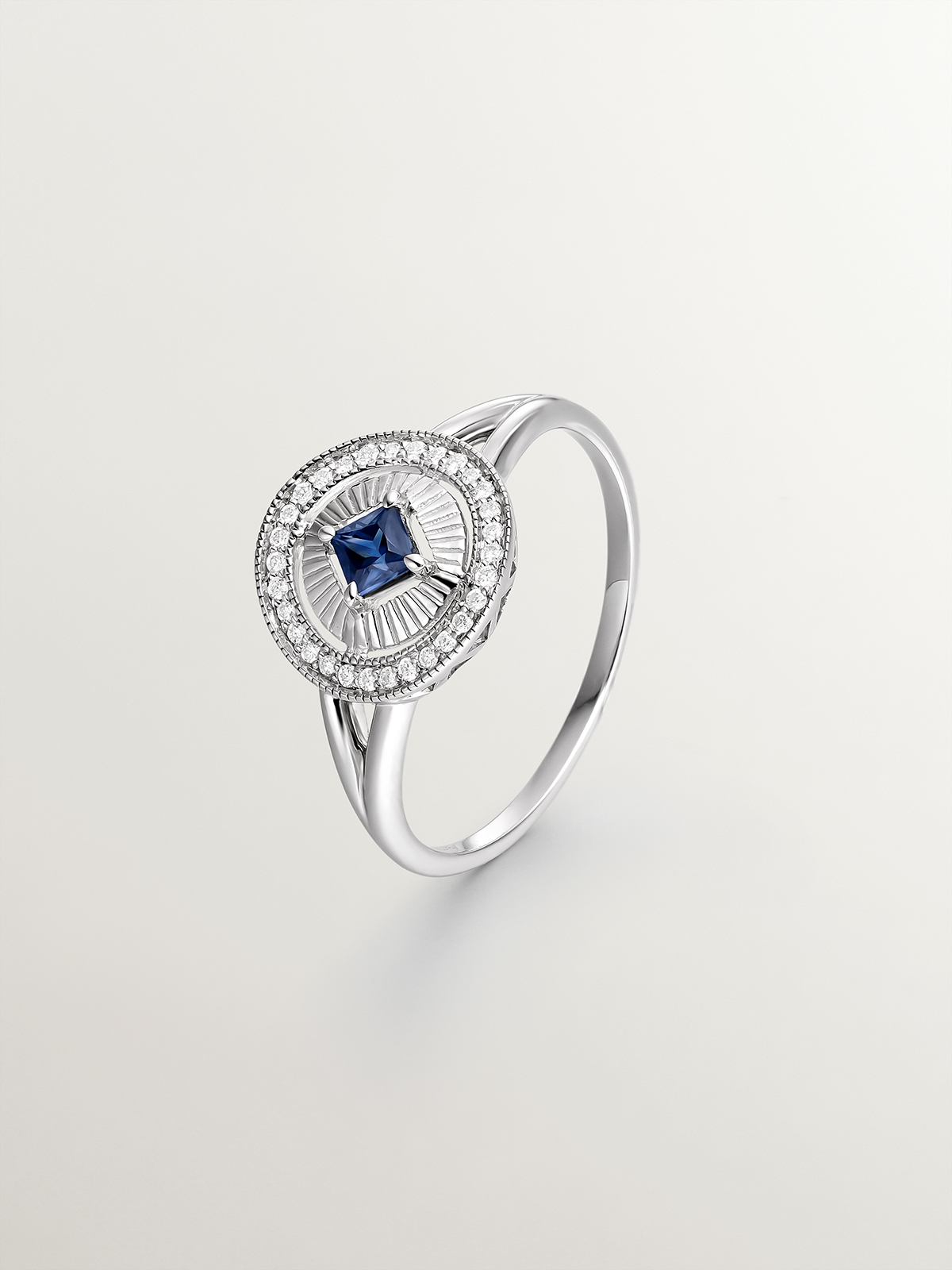 Anillo de oro blanco de 18K con diamantes en talla brillante y zafiro azul en talla princesa